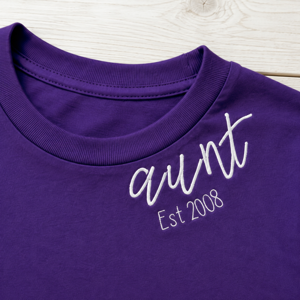 Established Script & Sleeve Names Tee. Curved-neck embroidery. Shown in: Gildan • Purple.