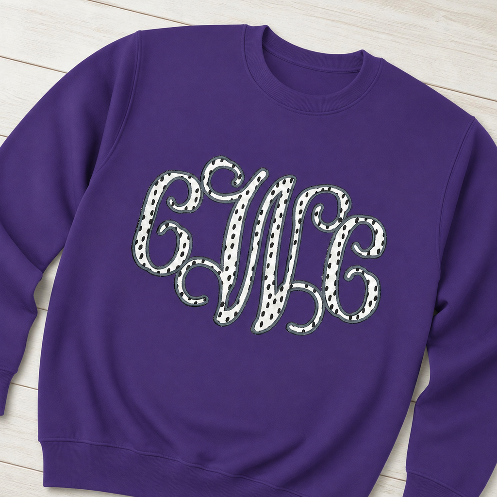 Styled flat lay of black dot vine monogram on Gildan 18000 Purple sweatshirt