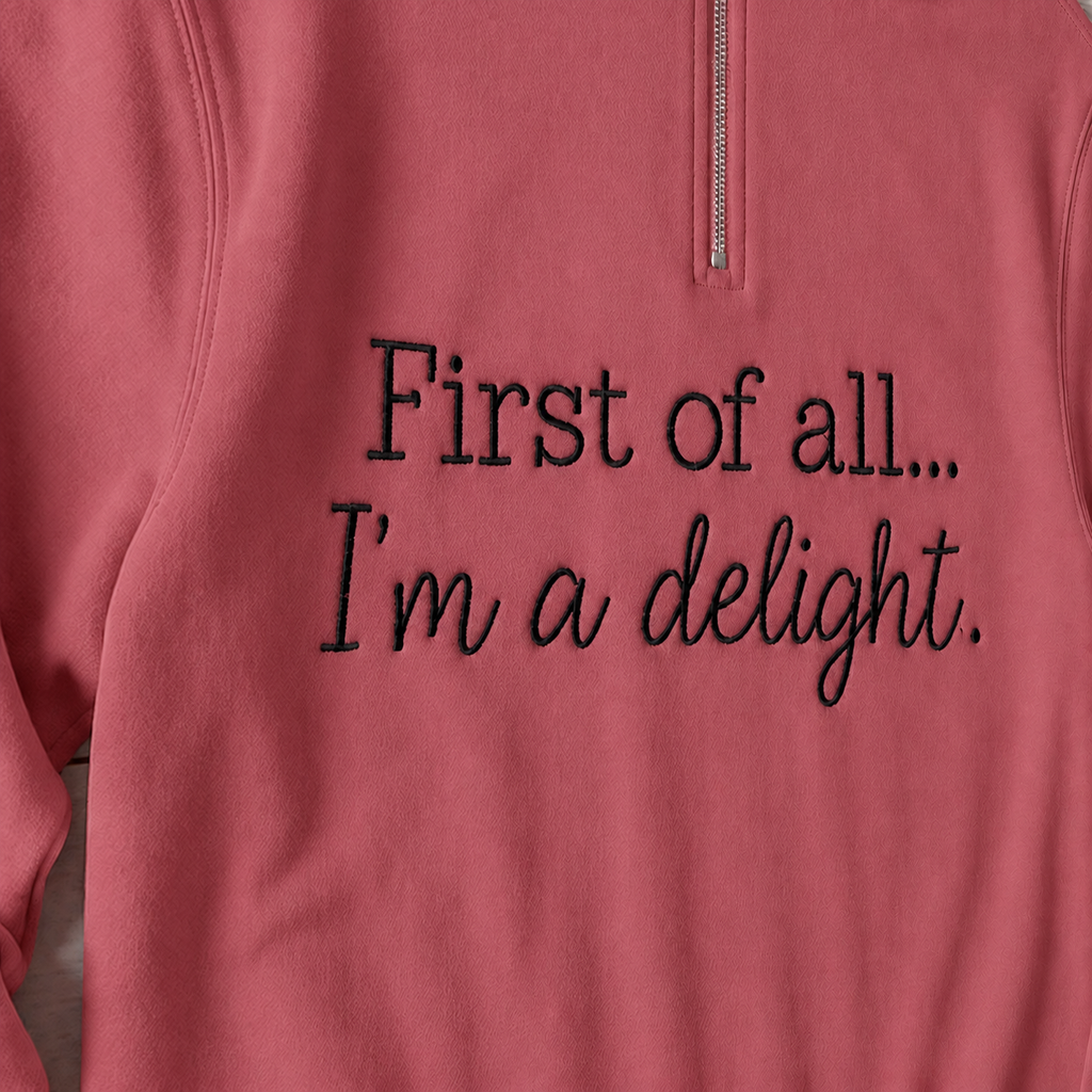 Close-up of enlarged black First of all... I'm a delight. embroidery on Comfort Colors G1580 Crimson quarter-zip
